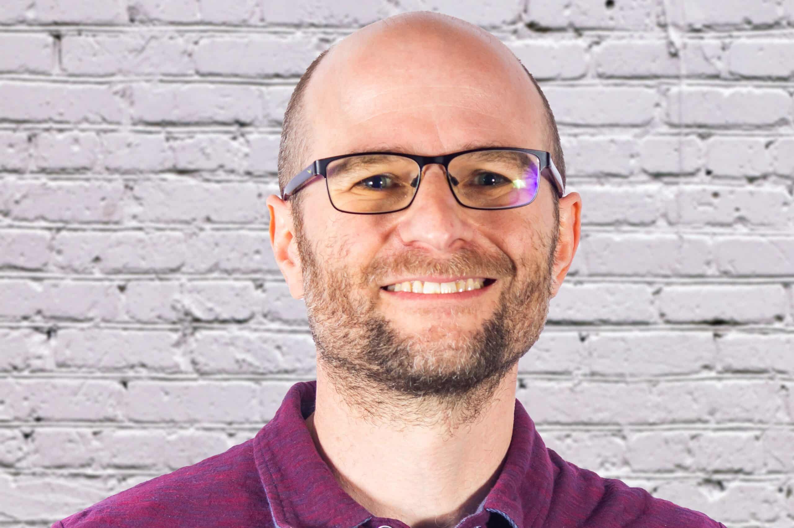 Ira Horowitz, co-founder of Cornershop Creative, smiling in purple shirt and glasses.