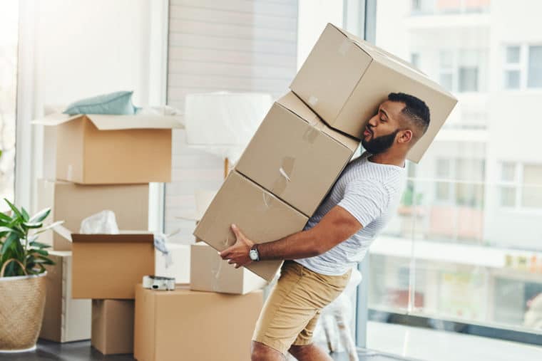 A man carrying a tower of cardboard moving boxes symbolize the process of caring for data migration for nonprofits