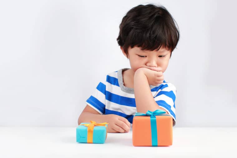 Choose a CRM blog post: Image of boy contemplating two small gift packages in front of him.