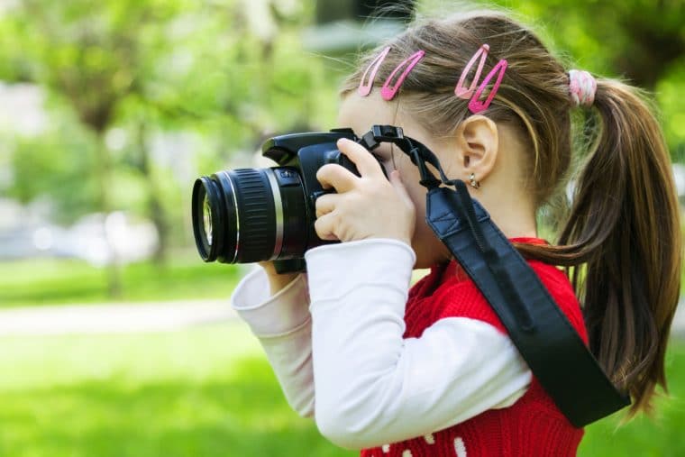 A young girl with a red shirt holds a camera to her eye. Featured image for planning images.