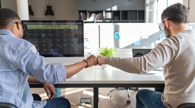 Two colleagues share a fist bump to celebrate the work they're doing together. Read this guide to learn more about the top nonprofit consultants for digital fundraising, marketing, and more.