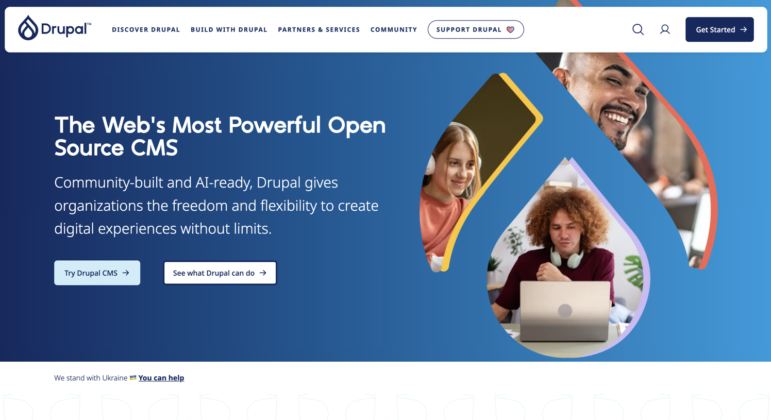 Screenshot of Drupal’s website homepage showing a blue banner with the text “The Web’s Most Powerful Open Source CMS,” ideal for nonprofit website builders, and images of people working on laptops. Navigation and call-to-action buttons are visible at the top.